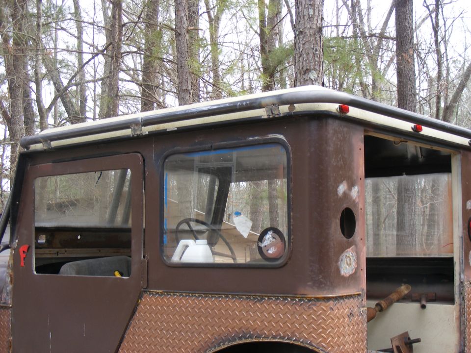 Side view of a rusty brown SUV with diamond plate trim and roll cage