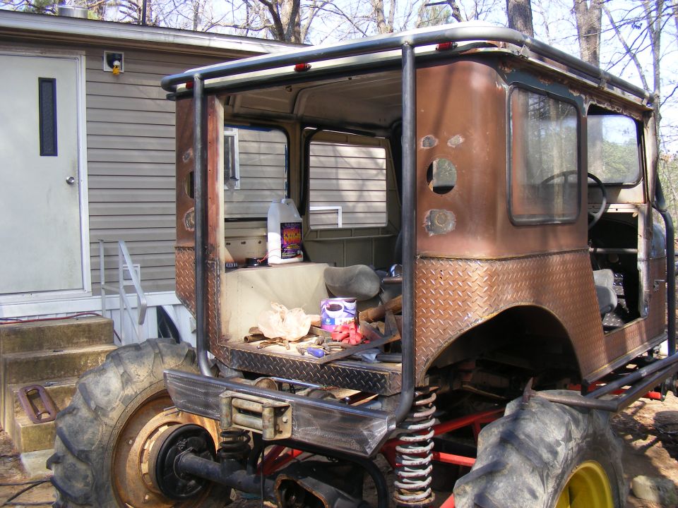 Custom off-road vehicle with large tires and roll cage, seen from the side