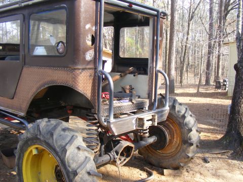Custom off-road vehicle with diamond plate fenders and large tractor tires, seen from the rear