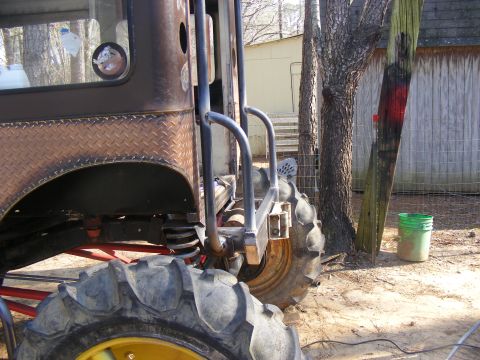 Back corner of a heavily modified vehicle with large tractor tires and diamond plate body panels. Roll cage tu