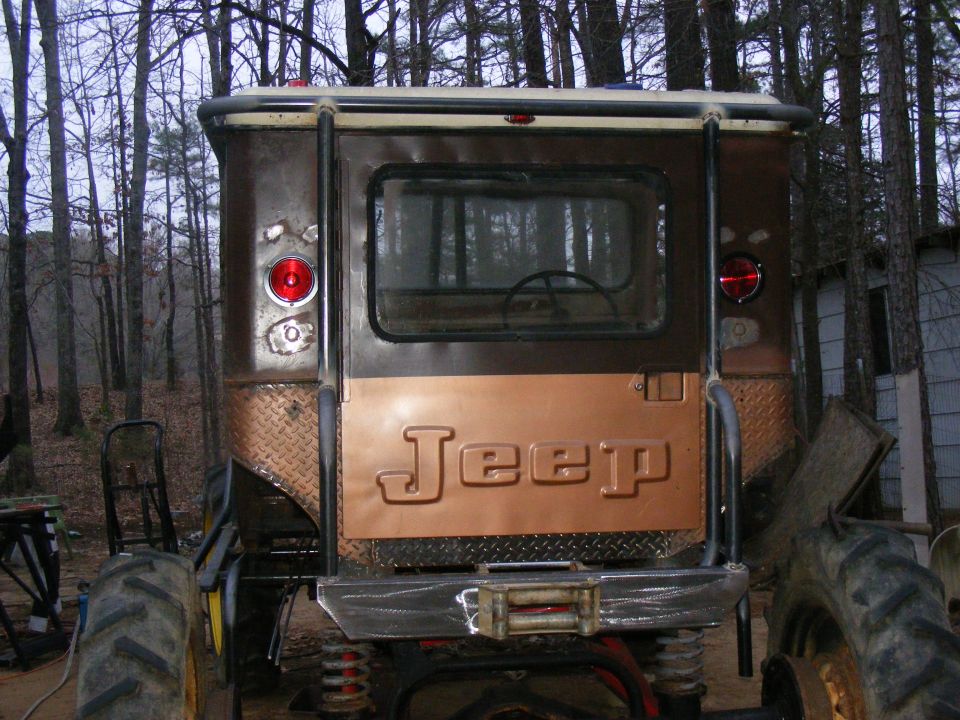 Rear view of a brown Jeep CJ-5 with a copper tailgate and large tractor tires