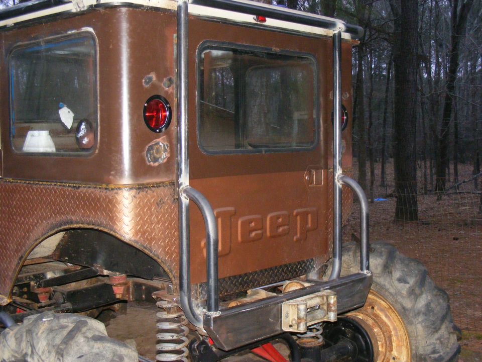 Rear view of a modified Jeep CJ with diamond plate fenders and custom roll cage. "Jeep" is embossed on the tailgate