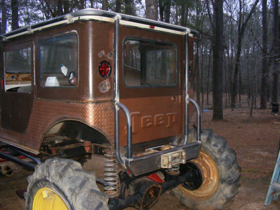Modified Jeep CJ-5 with large tires and roll cage, seen from the rear