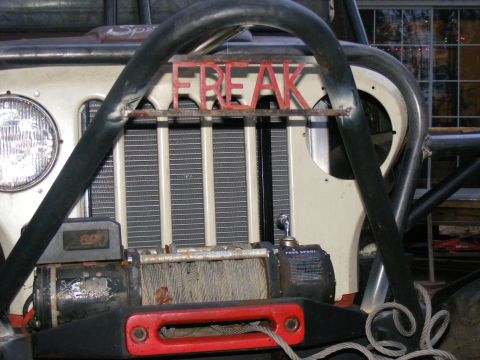 Off-road vehicle front with winch and red "FREAK" lettering on roll cage