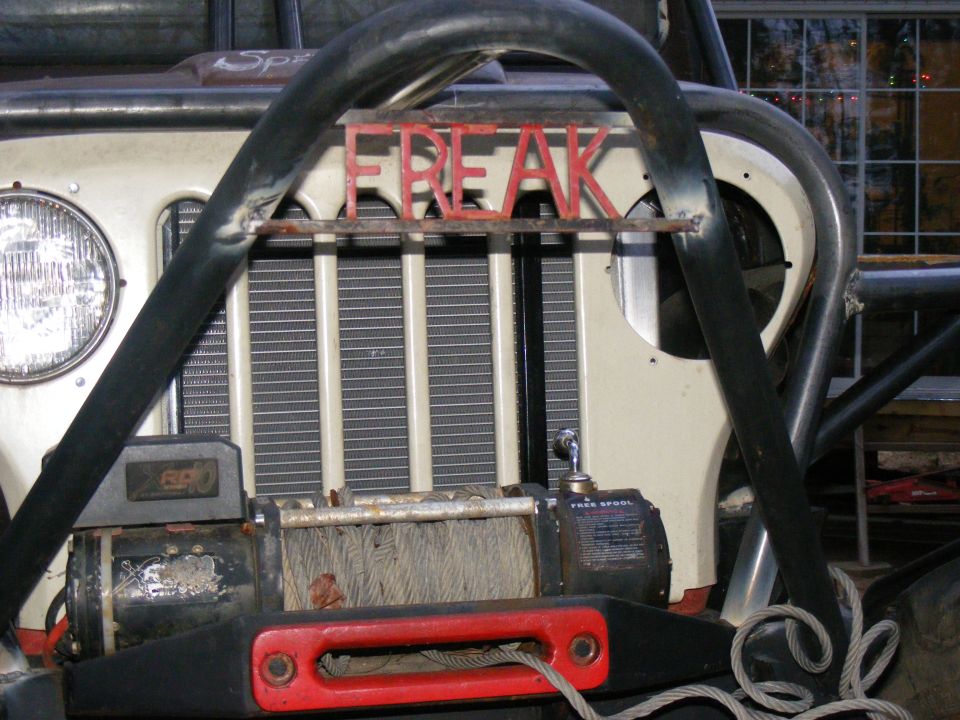 Off-road vehicle front with winch and red "FREAK" lettering on roll cage