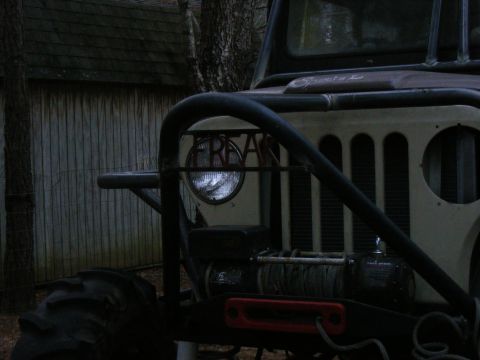 Front of a heavily modified Jeep CJ with a winch and roll cage. The word 'FREAK' is visible on the headlight