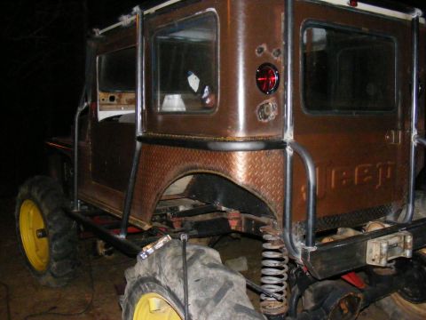 Brown off-road vehicle with large tires and roll cage, rear view