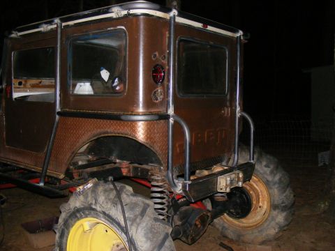 Custom brown off-road vehicle with large tires and roll cage. Looks like a modified Jeep
