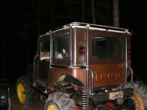 Brown Jeep with yellow wheels and large tires, rear view. Custom roll cage and diamond plate fenders