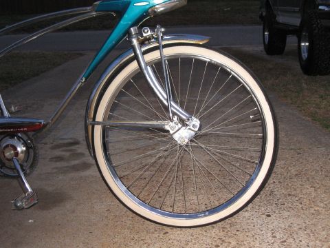 1994 Ford Bronco - A vintage bicycle with whitewall tires is parked on a concrete surface, with a truck in the background.