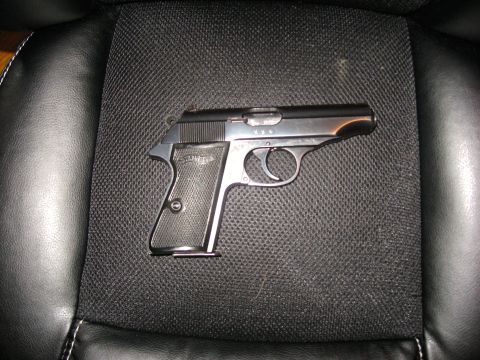 1992 Ford Mustang - A Walther PPK pistol rests on a car seat, its metallic finish reflecting light.