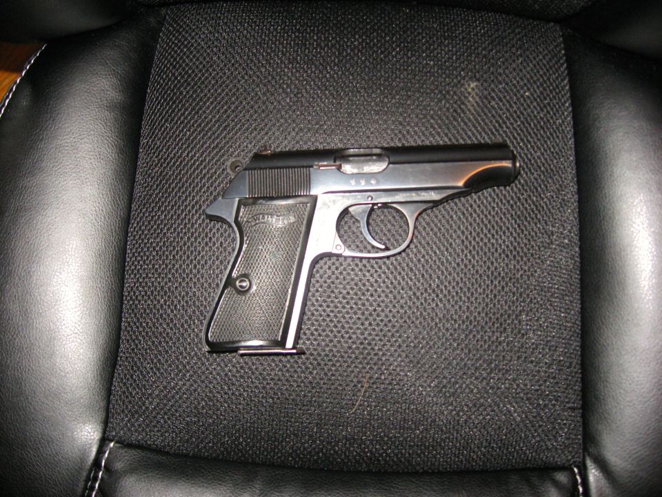 Walther PPK pistol on black car seat with white stitching
