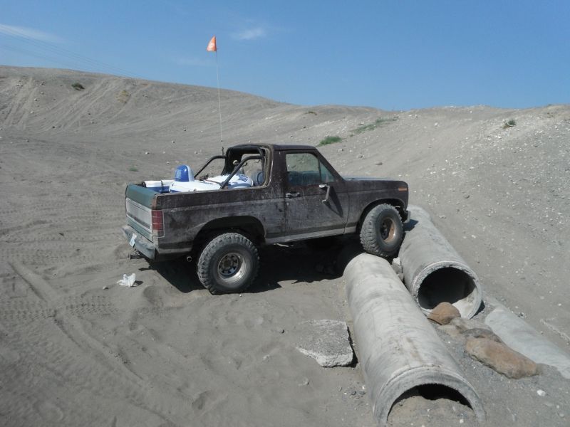 Brown 1980 Ford Bronco navigating concrete pipes off-road