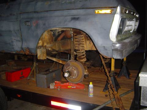 1986 Ford Bronco - A heavily rusted Ford F-150 truck is elevated on jack stands, revealing its suspension and undercarriage.