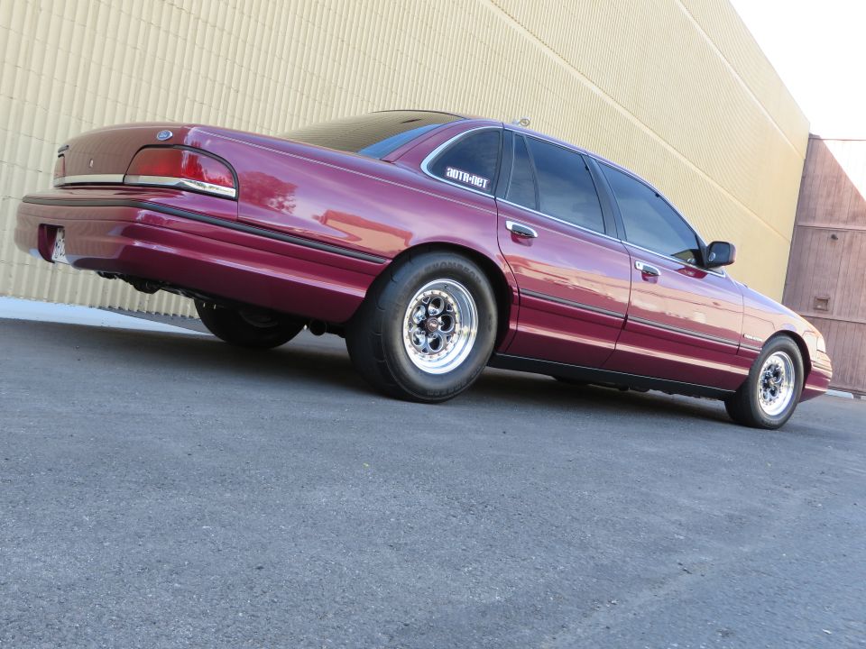 Maroon Ford Crown Victoria on drag wheels, low rear three-quarter view