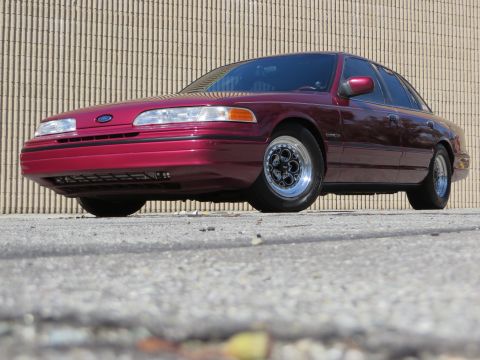 1992 Ford Crown Victoria - A maroon 1992 Ford Crown Victoria is shown from a low angle, highlighting its Weld Magnum III wheels.
