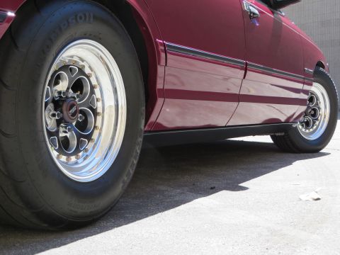 1992 Ford Crown Victoria - Close-up of a maroon sedan's side, highlighting its Weld Magnum III wheels and drag tires.