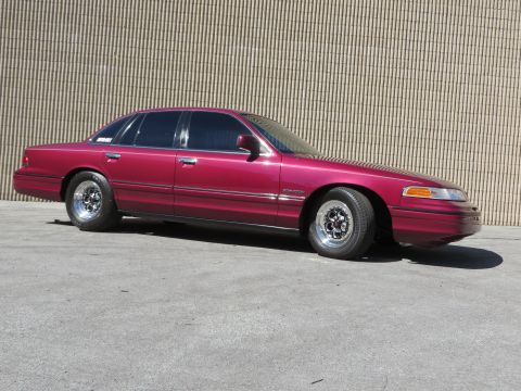 1992 Ford Crown Victoria - Side view of a maroon 1992 Ford Crown Victoria modified with Weld Magnum III wheels.