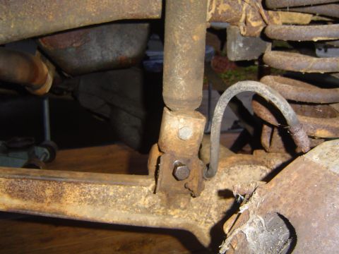 1986 Ford Bronco - Detail of heavily corroded truck suspension components, including a shock absorber and coil spring.