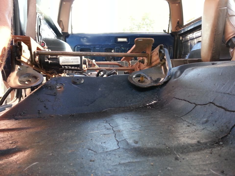 Interior view of vehicle floor with seat mounting hardware visible