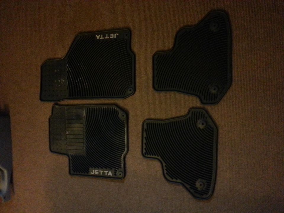 Four black rubber car floor mats, two with 'JETTA' embossed