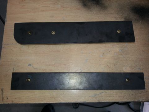 1994 Ford Bronco - Two metal brackets are shown on a wooden surface, possibly for vehicle modification or repair.