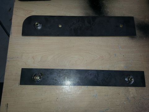 1994 Ford Bronco - Two metal brackets with visible weld marks and handwritten text are laid out on a wooden surface.