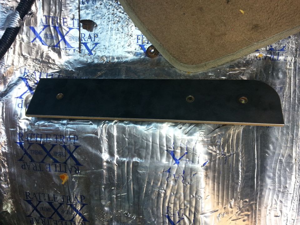 Sound deadening material on floor with a black trim piece screwed down