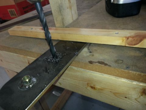 1994 Ford Bronco - A drill bit creates shavings as it bores through a metal plate secured with a bolt and nut.