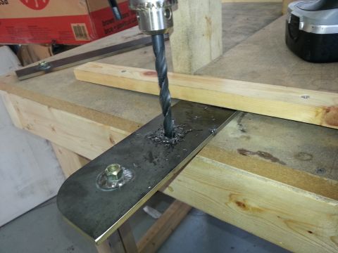 1994 Ford Bronco - A drill bit bores through a metal plate, creating metal shavings around the hole.