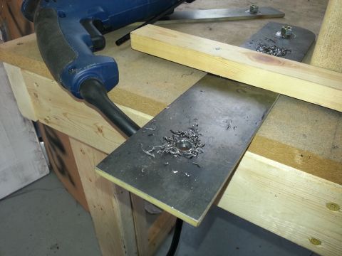 1994 Ford Bronco - Metal plate with a freshly drilled hole and metal shavings, next to a drill.