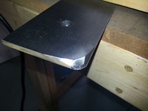 1994 Ford Bronco - A metal bracket with a hole is shown on a wooden surface.