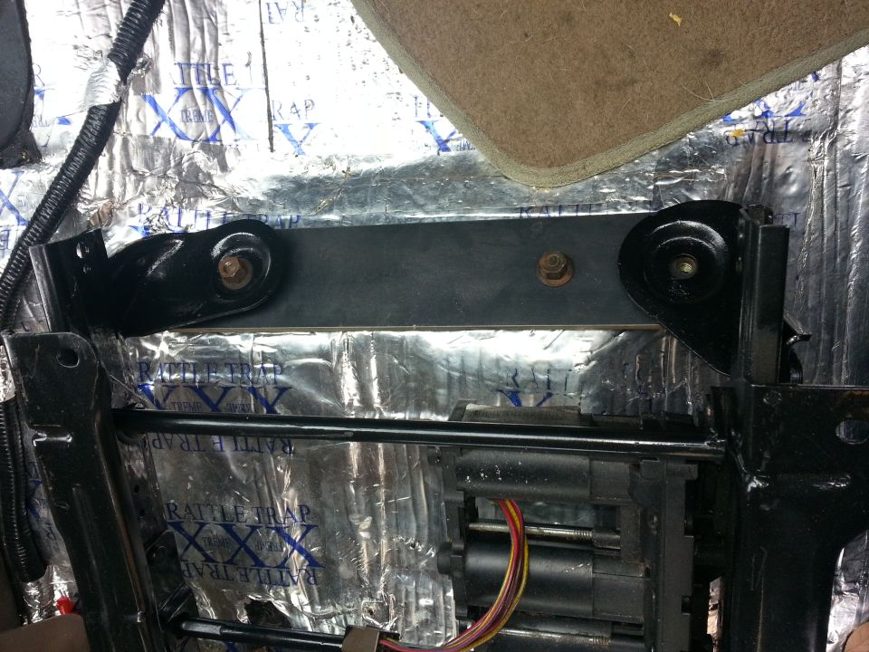 Seat mounting bracket with bolts and wiring, covered in sound dampening material