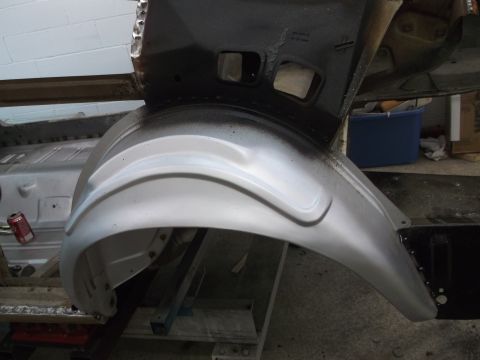 1967 Ford Mustang - Close-up view of a vehicle's rear wheel well and surrounding chassis, showing metalwork and primer.
