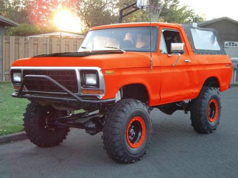1994 Ford Bronco - This lifted orange Bronco features a removable soft top and a front bull bar, suggesting a late 1970s model.