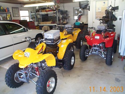 1978 Ford Bronco - A collection of ATVs are stored inside a garage, with a white car parked alongside them.
