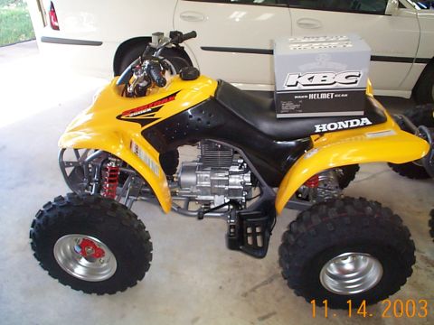 1978 Ford Bronco - A yellow Honda ATV is parked indoors, with a box of helmet gear placed on its seat.