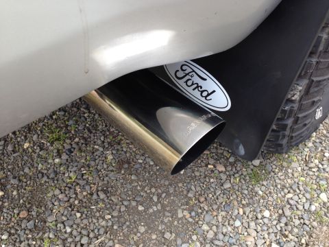1992 Ford F-150 - A chrome exhaust pipe and a Ford-branded mud flap are visible on the rear of a vehicle.
