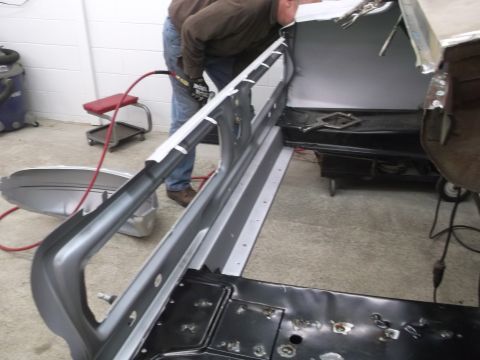 1967 Ford Mustang - A person works on the interior metal structure of a car during a repair process.