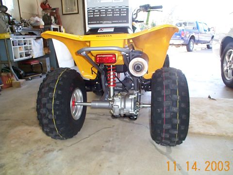 1978 Ford Bronco - Yellow Honda ATV shown from the rear, parked indoors with other vehicles visible.