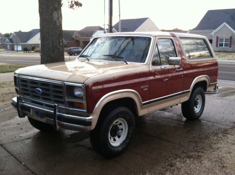 1986 Ford Bronco - This two-tone Ford Bronco is parked outside a suburban home on a cloudy day.