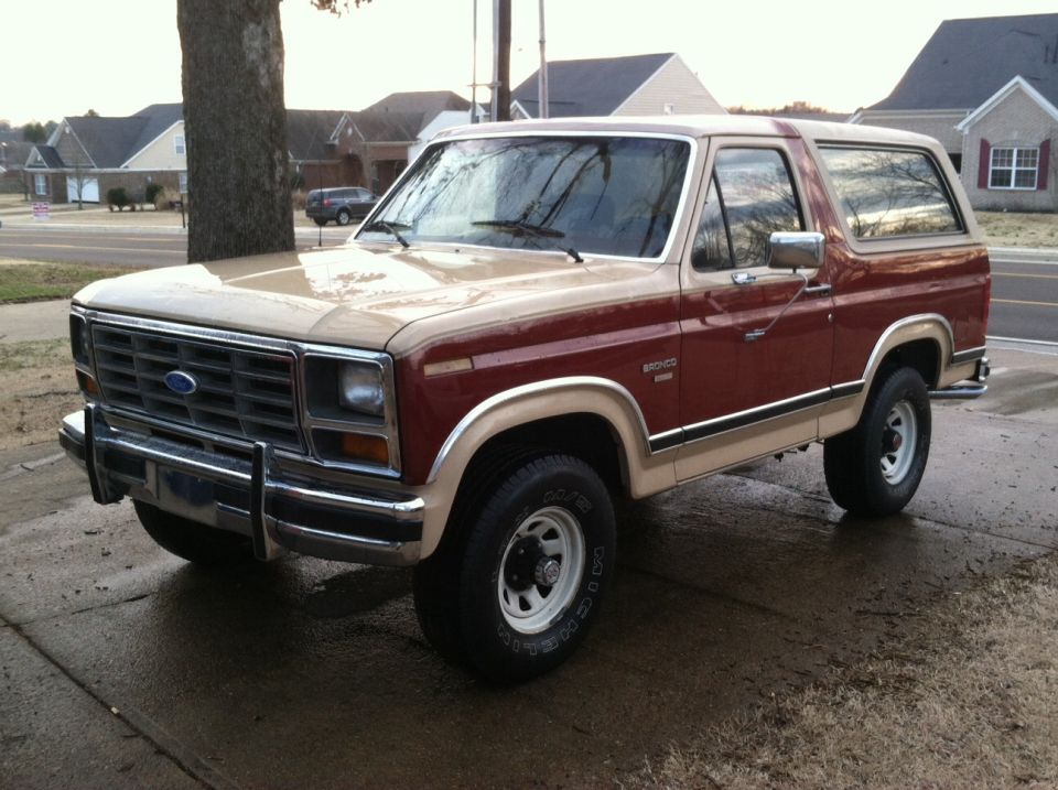 Two-tone red and tan Ford Bronco parked on a wet driveway