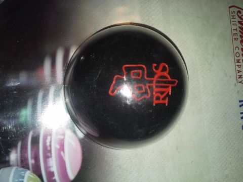 1968 Ford Bronco - A black shift knob a red RIPS logo is shown, with text from a shifter company visible in the background.