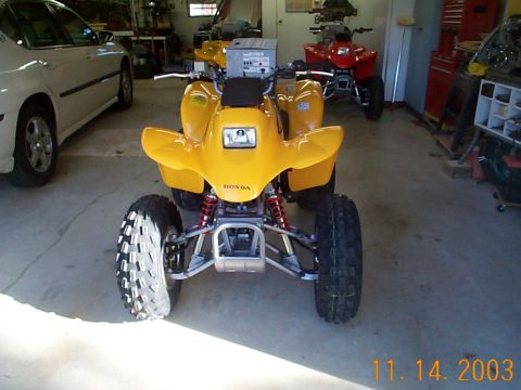 1978 Ford Bronco - A yellow Honda ATV is parked in a garage next to a white car and a red ATV.