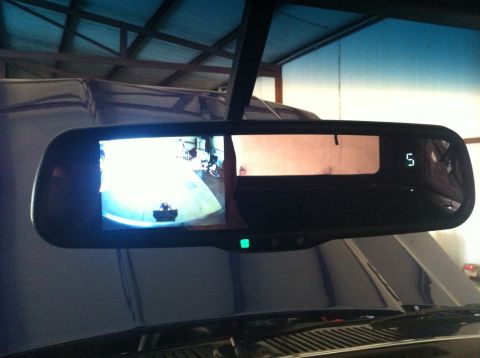1982 Ford Bronco - Interior shot of a rearview mirror displaying a backup camera feed and a digital clock.