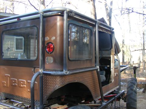 Custom Jeep CJ with roll cage and diamond plate fender flares, seen from the rear quarter