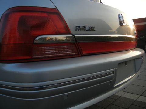 1999 Ford Fairlane - Close-up of the rear taillight and trunk of a silver sedan, showing the 'FAIRLANE' emblem.