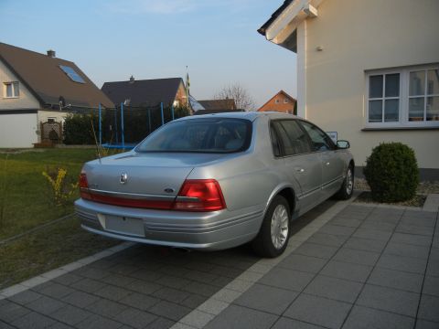 1999 Ford Fairlane - Silver sedan parked in a driveway next to a house. The rear of the car is visible.