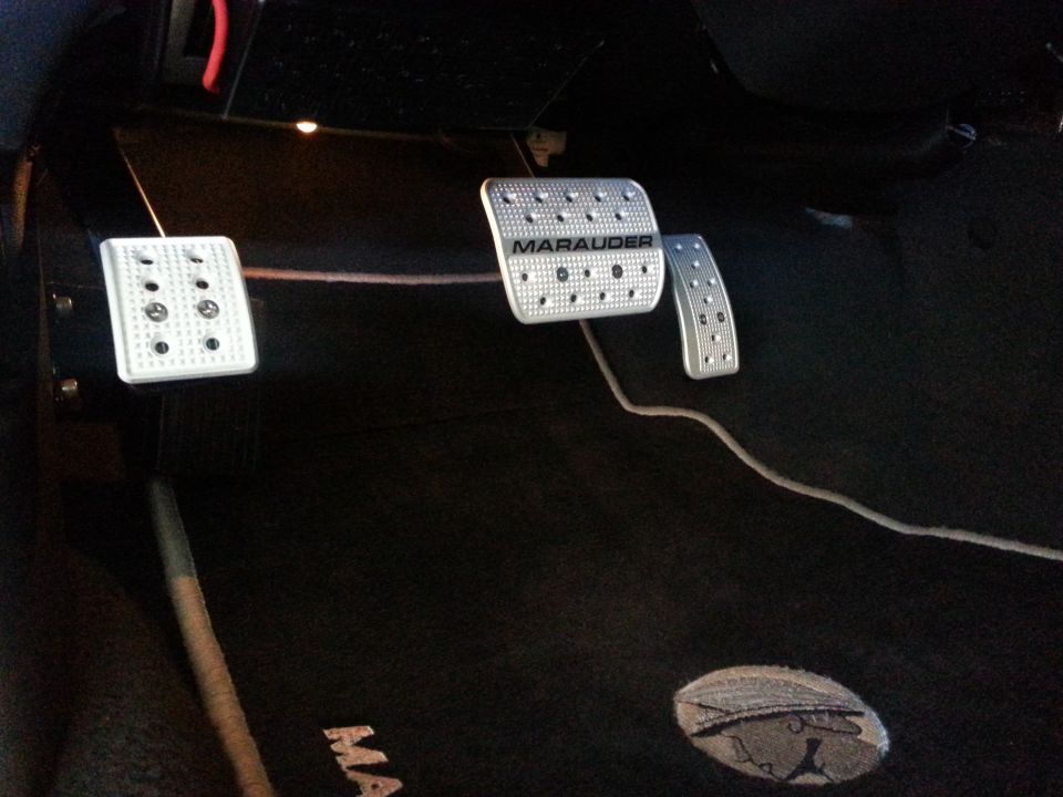 Aftermarket aluminum pedal covers with 'Marauder' text on the brake pedal, installed on a black floor mat