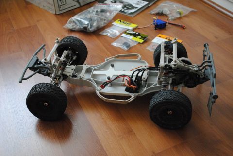 1986 Ford Bronco - This is a remote control car chassis with various parts laid out on a wooden floor.